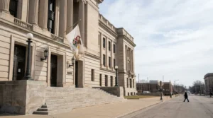 Illinois state flag hangs outside stone courthouse building with columned facade